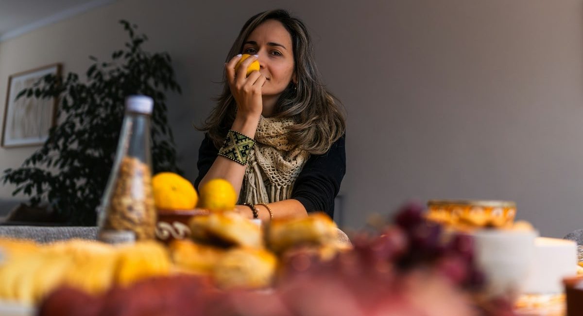 Woman smelling a lemon at a table with food