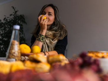 Woman smelling a lemon at a table with food