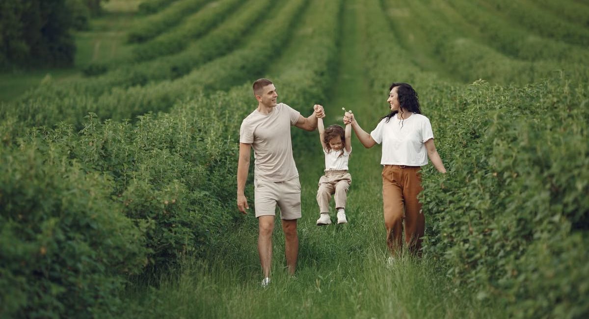 A happy family walking in a lush, green rural field together.